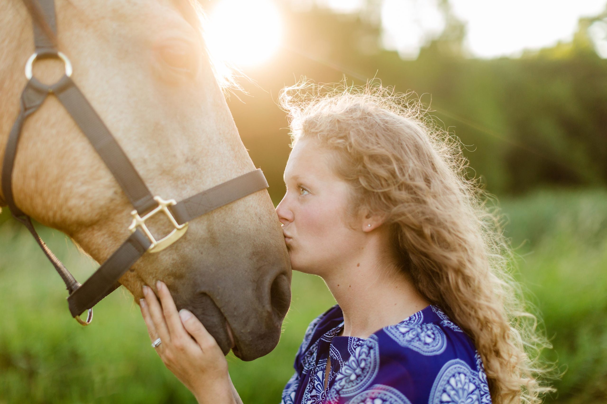 girl kissing her horse in the sun