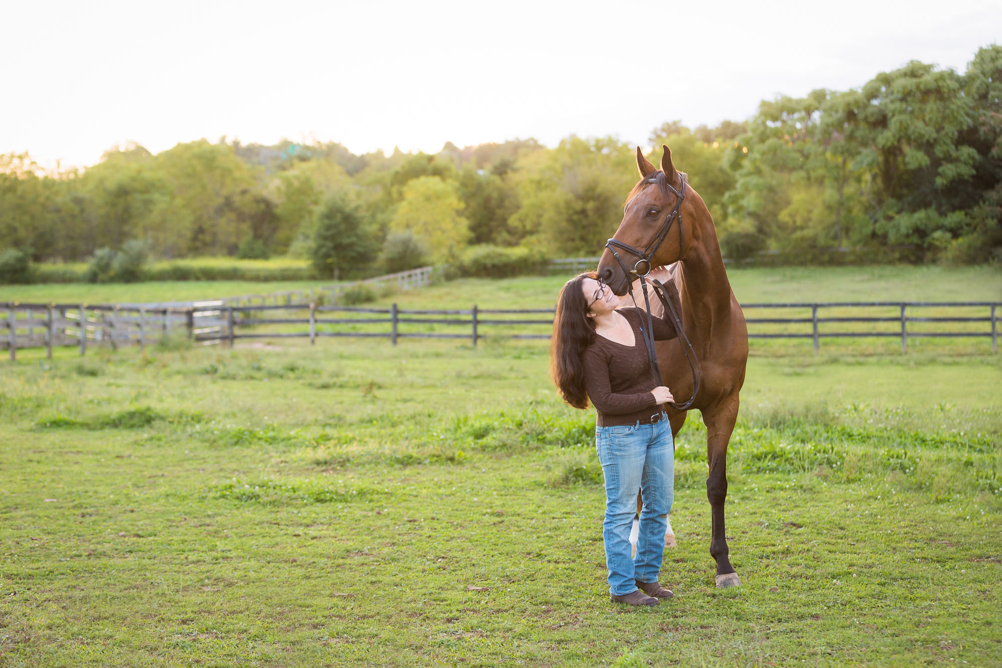woman being kissed by gelding horse in a green field