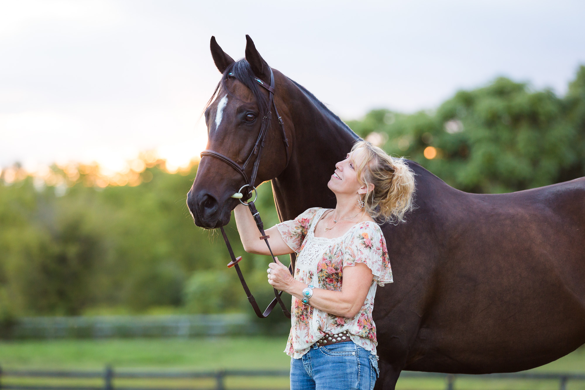 woman smiling and holding bay gelding OTTB horse