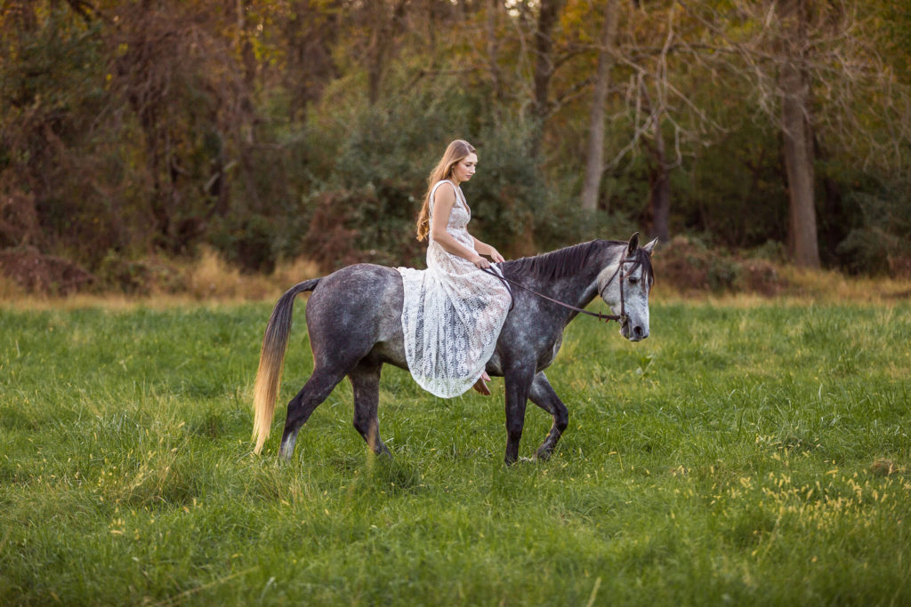 girl in white dress riding dapple grey pony