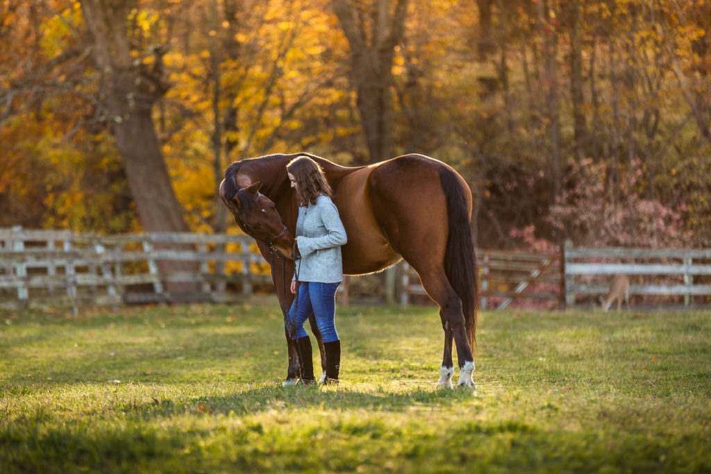 girl in field at sunset with horse