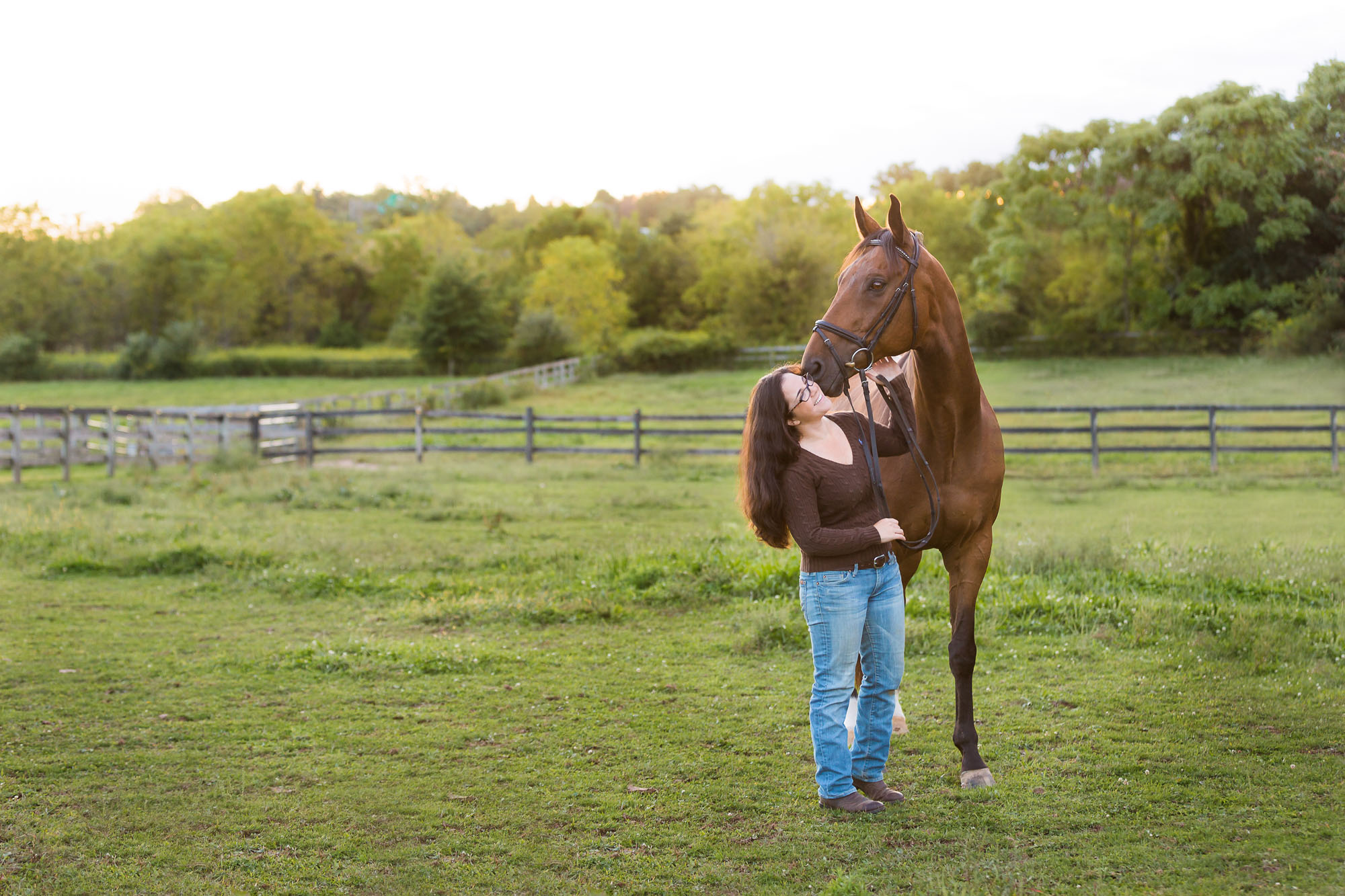 girl in brown sweater and jeans with bay horse