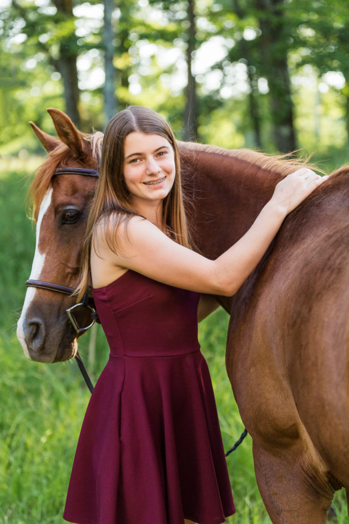 girl in burgundy dress hugging a chestnut mare at The Black Fox Farm
