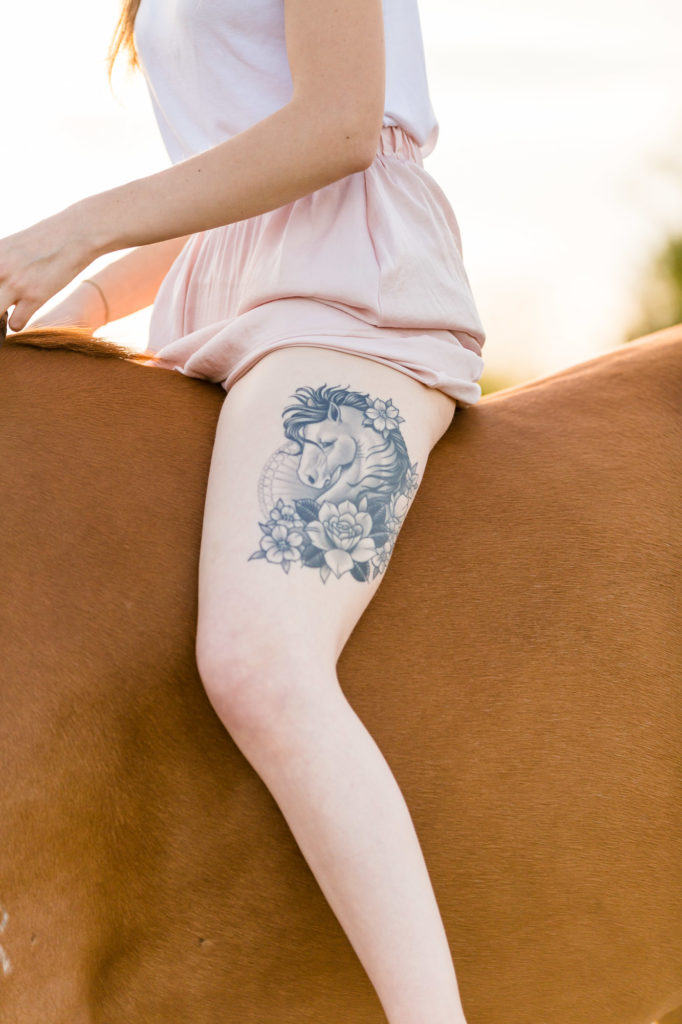 leg tattoo on a girl with a pink skirt sitting astride her mare