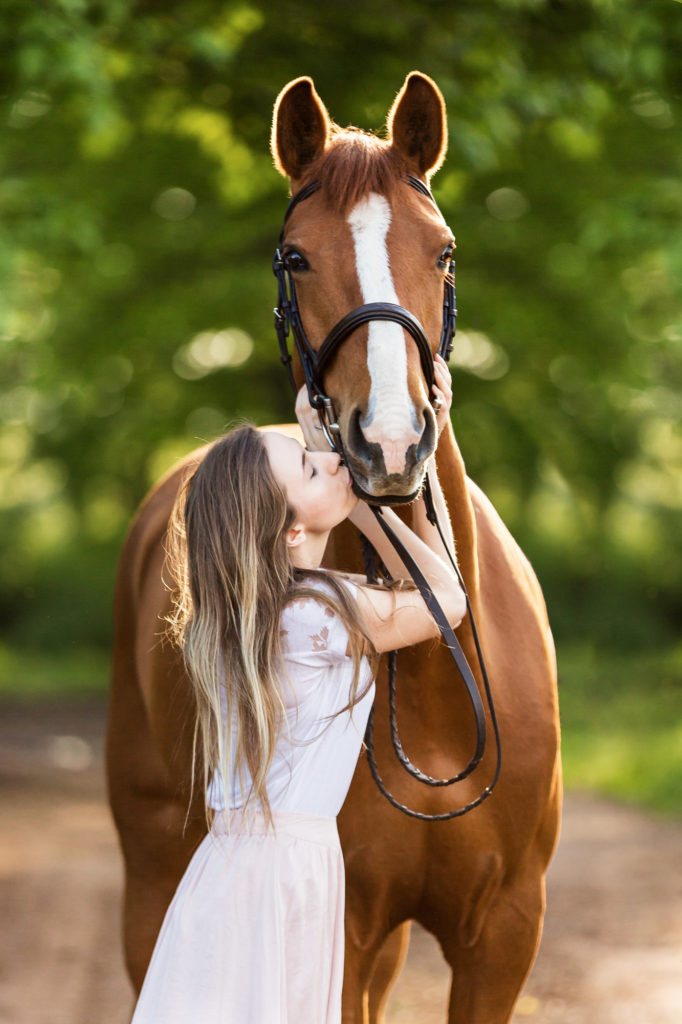 girl in pink skirt kissing her chestnut mare at Magnolia Creek Stables