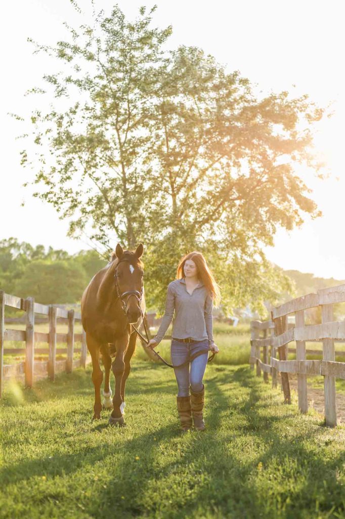 red headed girl walking her horse in the sunset at Golden Gait Farm
