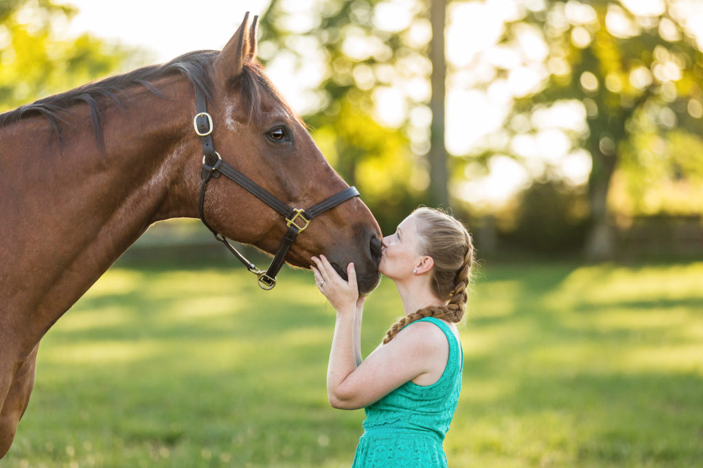 girl in turquoise dress kissing bay horse at Robin Hill Farm