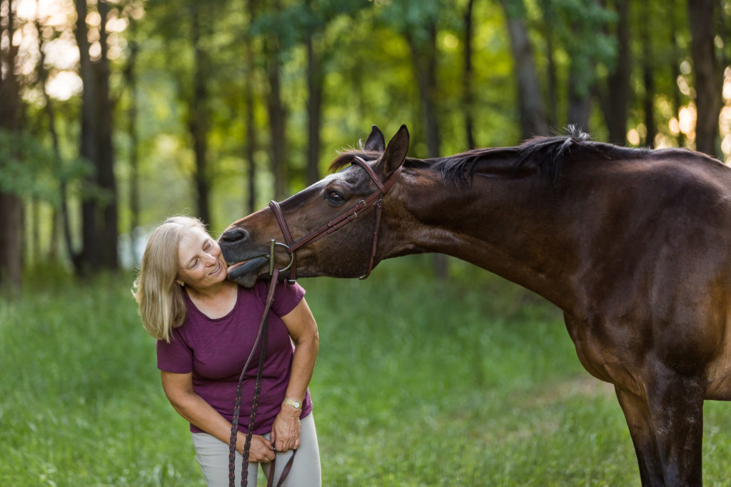 woman being kissed by her bay mare horse