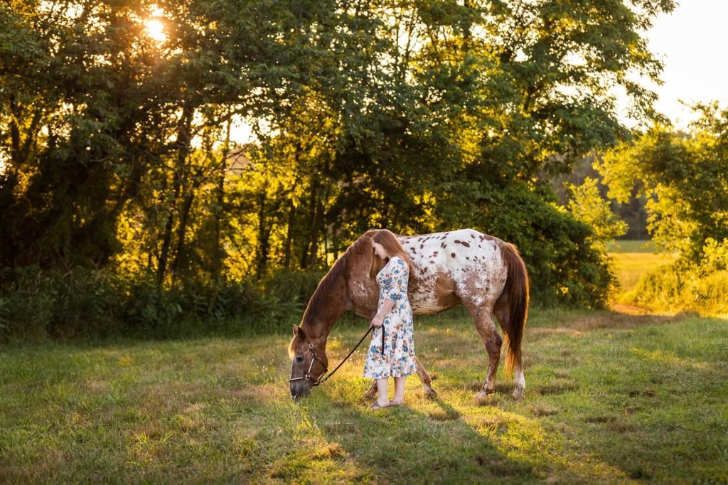 girl grazing an appaloosa horse in field at Tri-Brook Equestrian Center