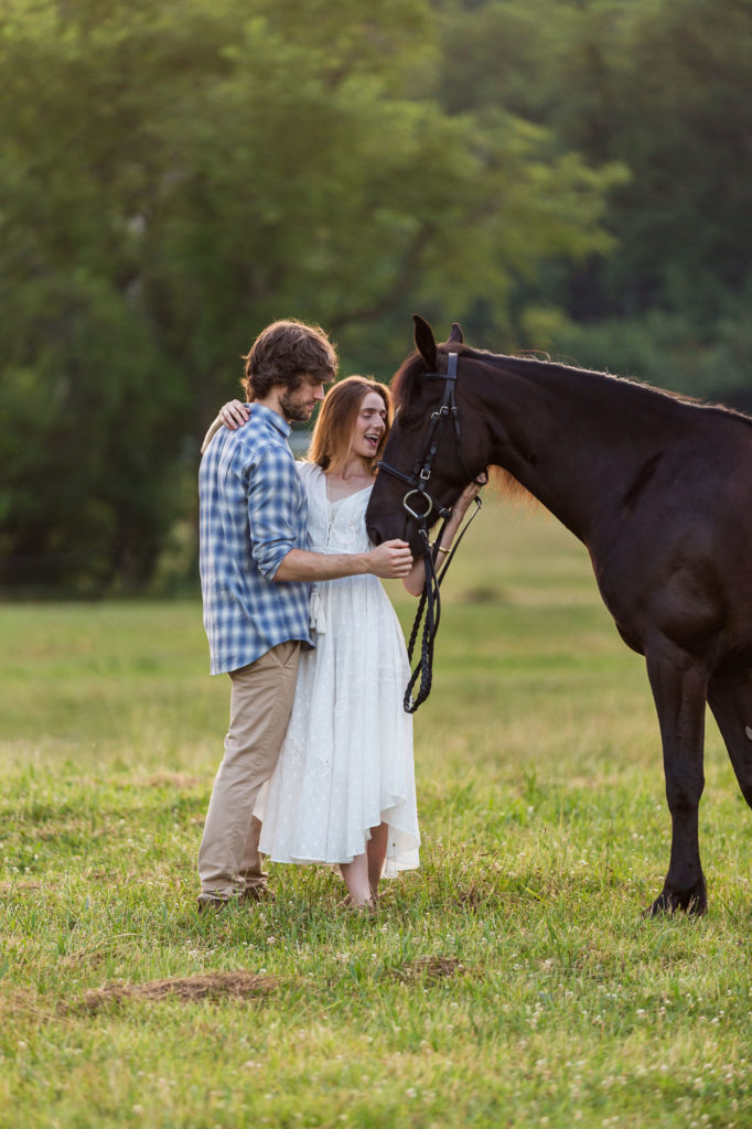 engaged couple with black horse at Great Scott Farm