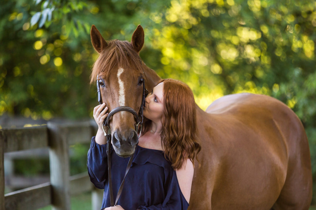 girl with red hair kissing her horse