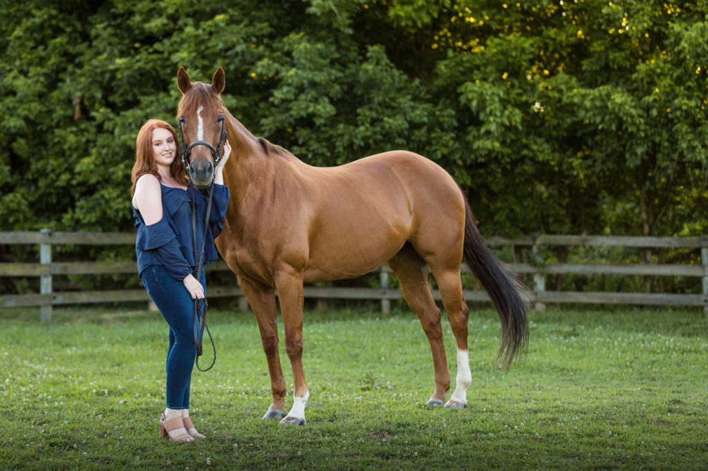 girl with red hair and blue top holding horse