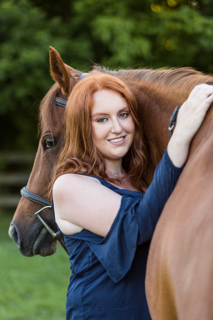 girl with red hair hugging chestnut horse