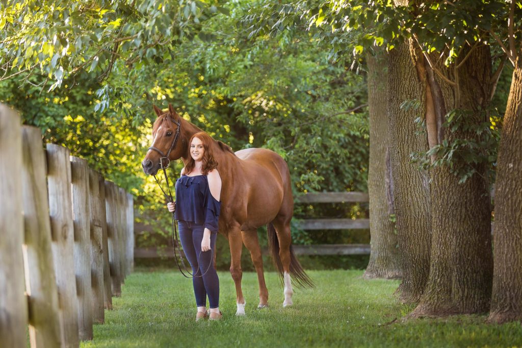 girl holding chestnut horse under trees at Sommerfield Stables