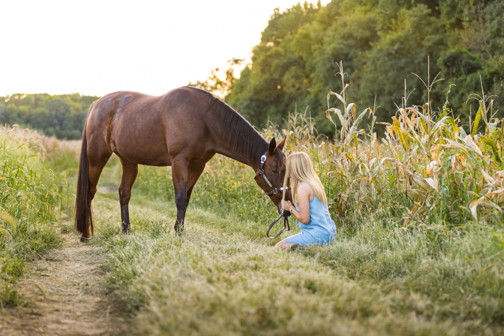 woman in blue dress sitting on ground with horse at Voight Farm