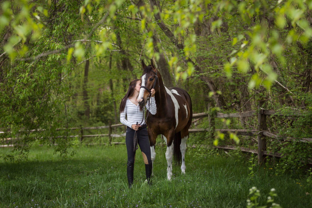 girl kissing her horse under the trees at Redfield Farm in Califon NJ