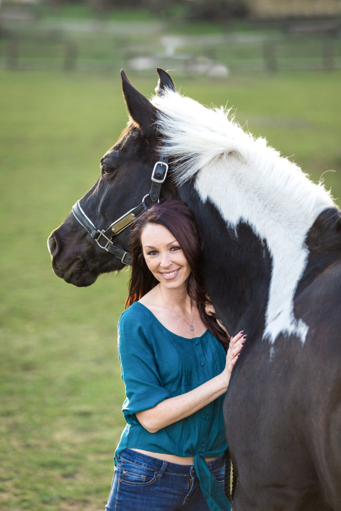 woman hugging black and white horse