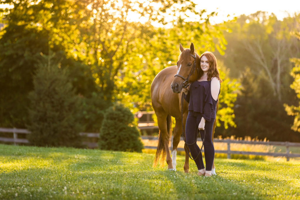 girl in blue top with horse at sunset in field at Sommerfield Stables