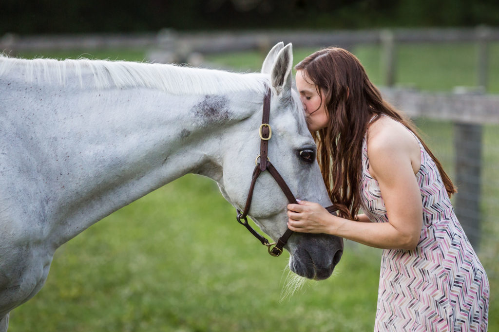 girl with long brown hair gently kissing her horses's face at Duck Crossing Farm