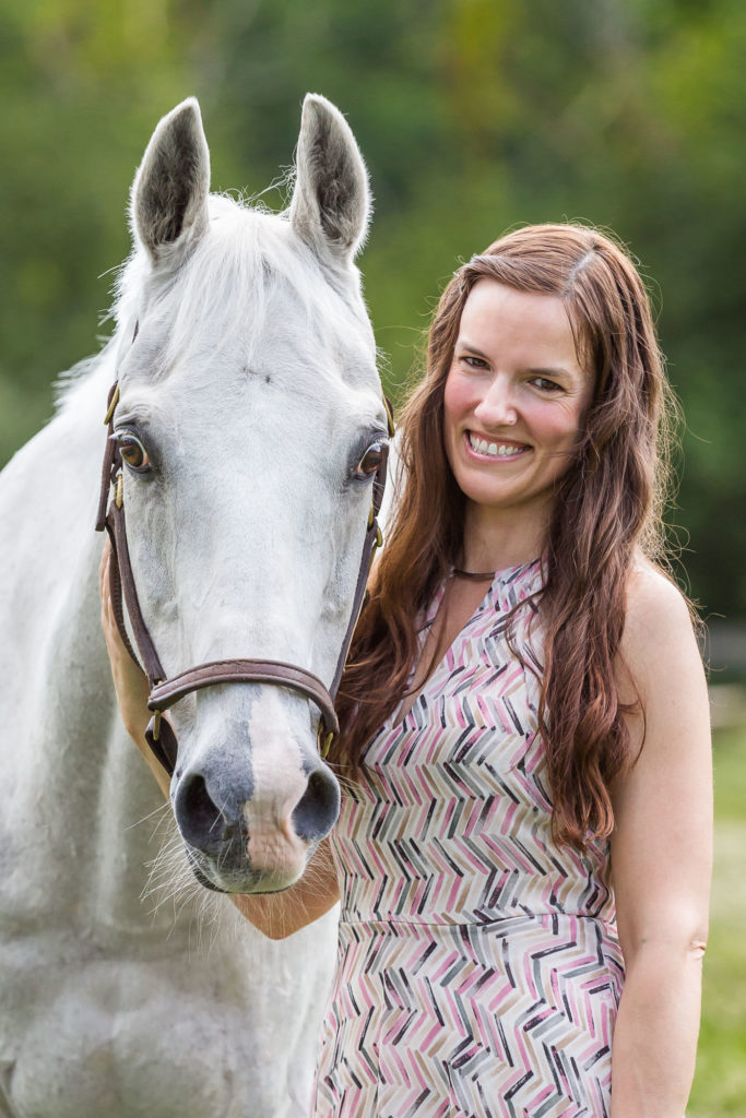 girl with long brown hair and white horse at Duck Crossing Farm