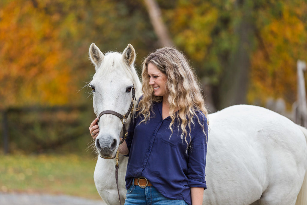 Carly standing next to her white horse, Hercules