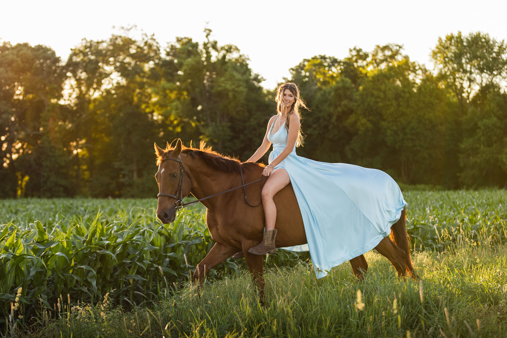 Alyssa rides Ben through a corn field at sunset