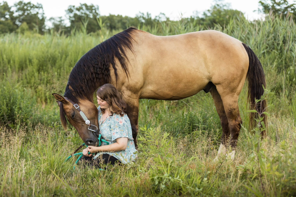 girl sitting in grass with her horse